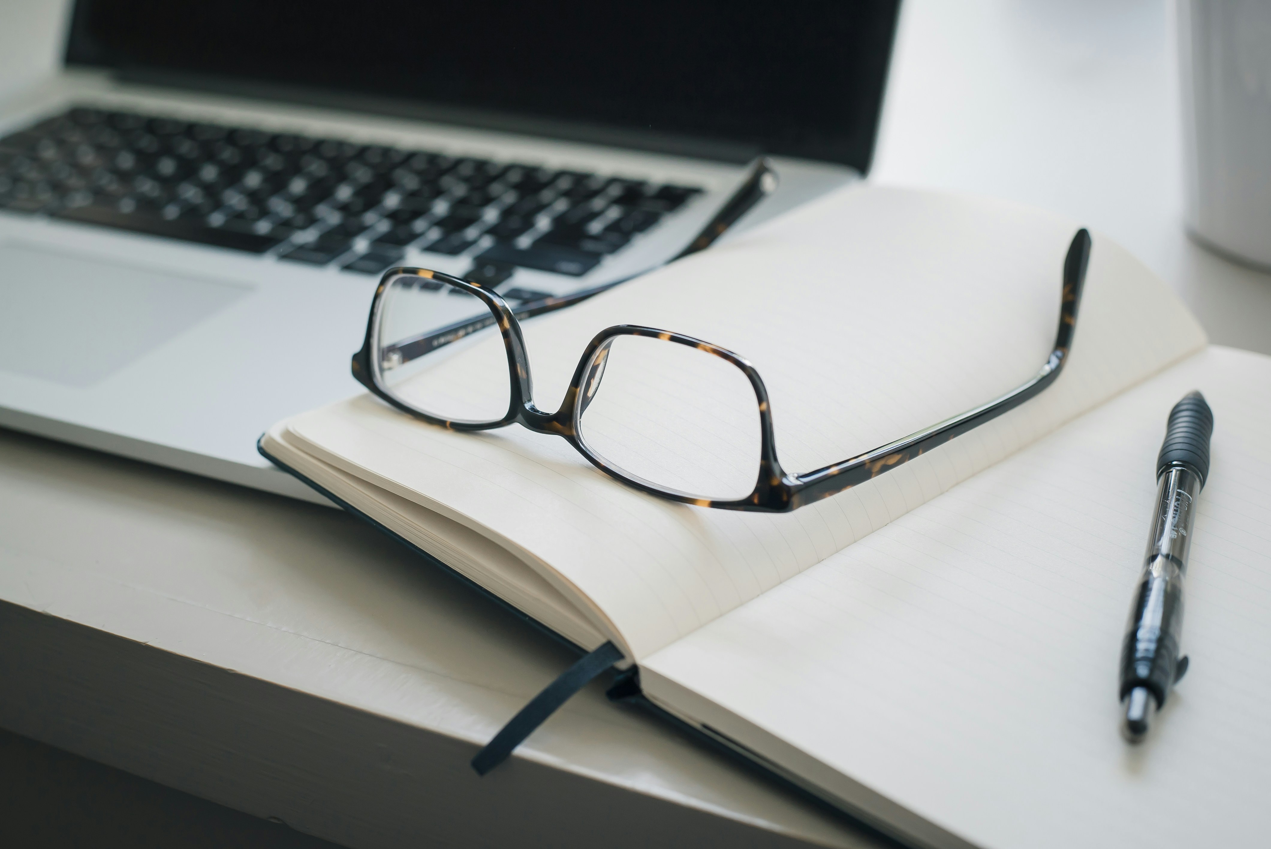 Desk with glasses, notebook, and keyboard